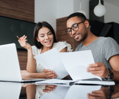 Cheerful loving young couple using laptop and analyzing finances